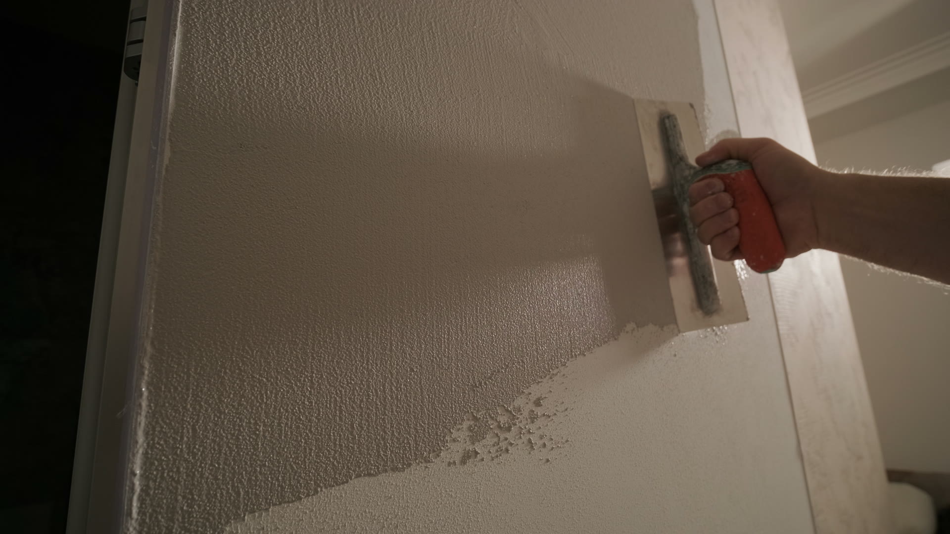 A steel trowel floating a fine poly-microcement coating smooth across an interior wall