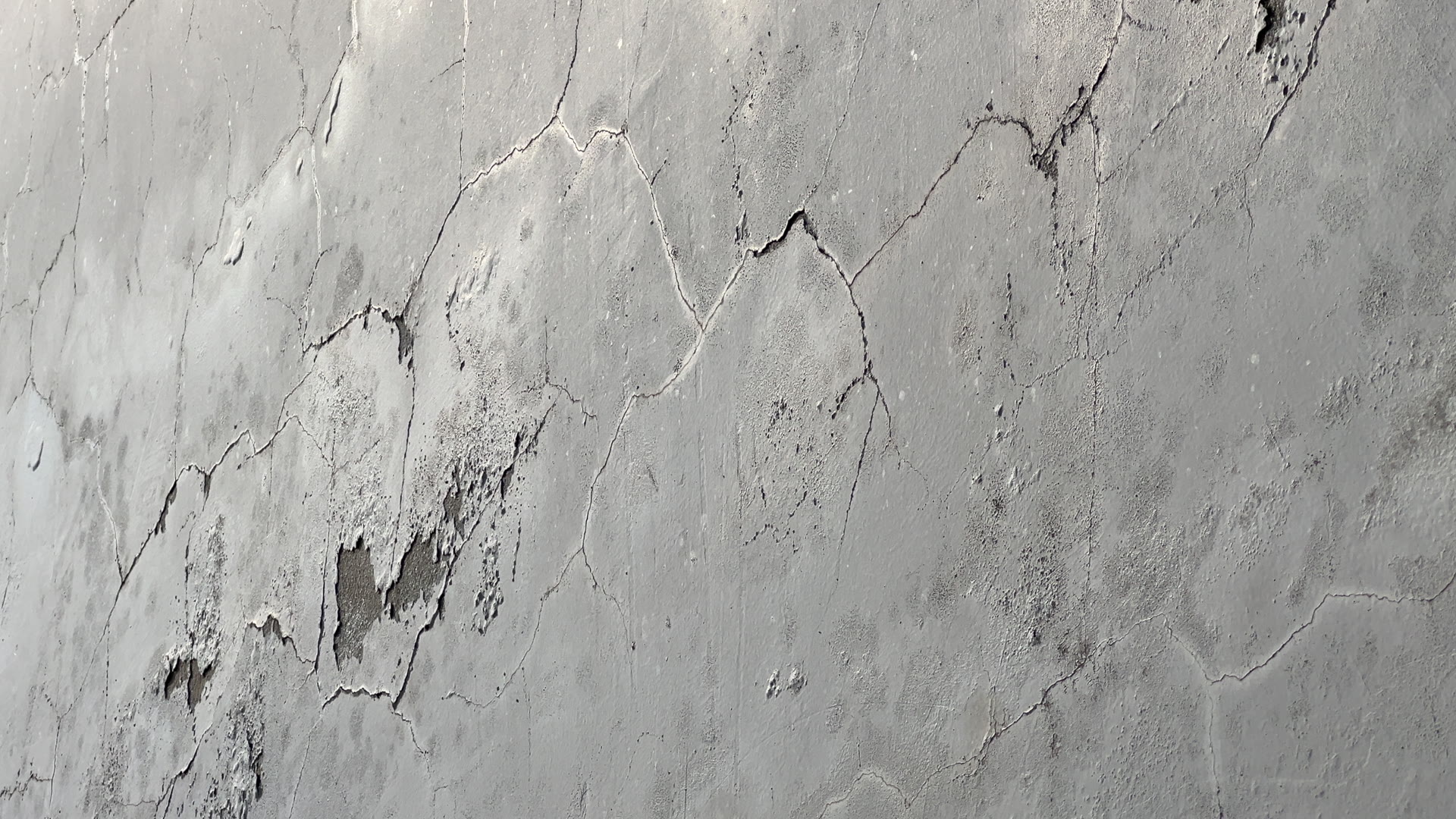 Close-up pan across a cracked, weathered render wall in need of remedial repair